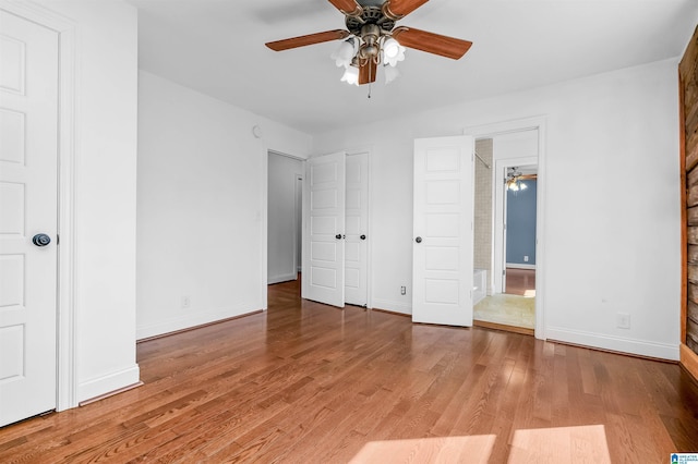 unfurnished bedroom featuring ensuite bathroom, ceiling fan, wood finished floors, and baseboards