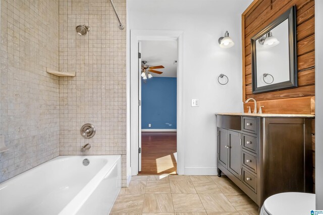 bathroom with toilet, a ceiling fan, tub / shower combination, vanity, and baseboards