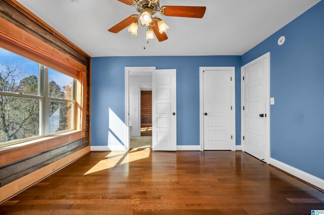 unfurnished bedroom with ceiling fan, wood finished floors, and baseboards