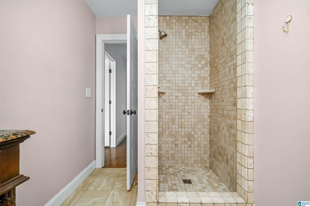 full bath with a tile shower and baseboards