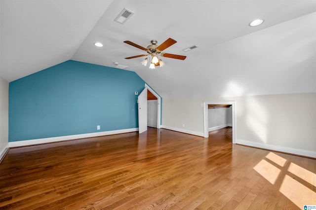 additional living space with vaulted ceiling, wood finished floors, visible vents, and baseboards