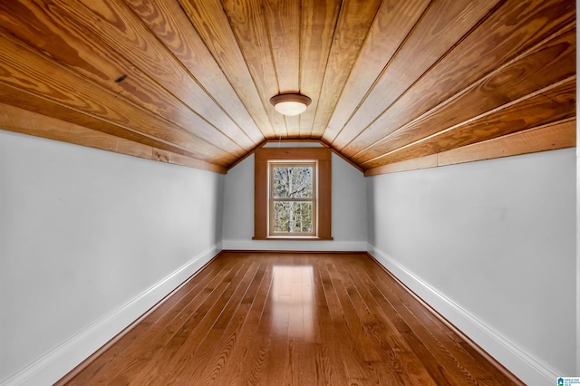 additional living space with dark wood-style floors, vaulted ceiling, wood ceiling, and baseboards