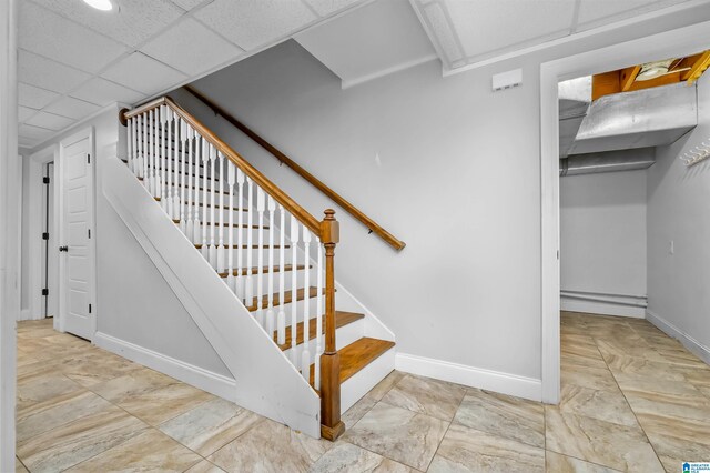 staircase with a drop ceiling and baseboards