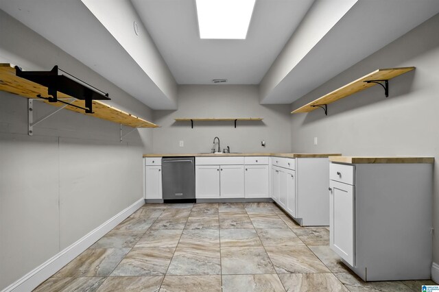 kitchen with white cabinets, a sink, open shelves, and stainless steel dishwasher