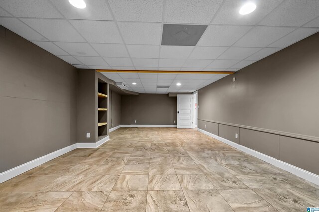 finished below grade area with baseboards, a drop ceiling, and recessed lighting