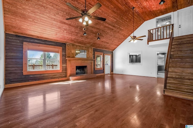 unfurnished living room featuring a fireplace with raised hearth, a ceiling fan, wood finished floors, high vaulted ceiling, and wooden ceiling