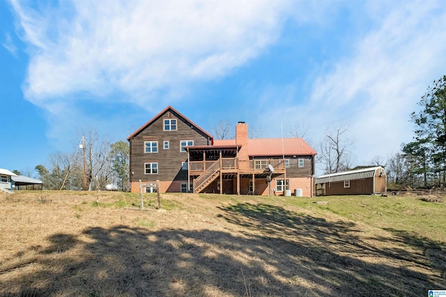 rear view of house featuring a yard, a chimney, stairway, metal roof, and a deck