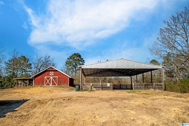 view of yard with an outbuilding, dirt driveway, a barn, and fence