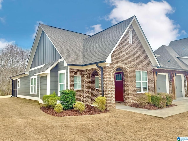 view of front of property featuring an attached garage, driveway, a shingled roof, and brick siding