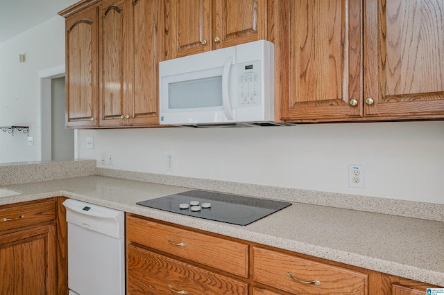 kitchen featuring brown cabinets, white appliances, and light countertops