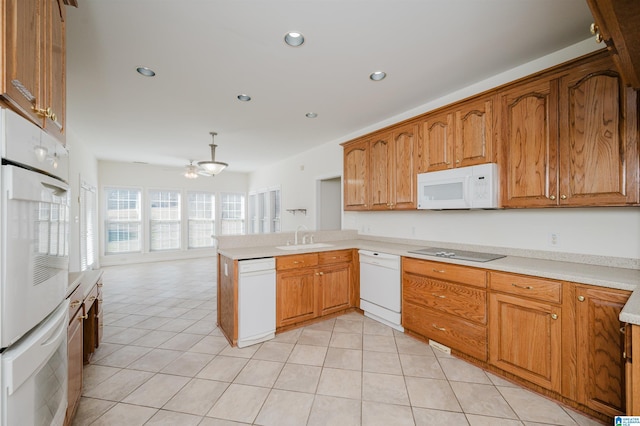 kitchen with light tile patterned floors, a peninsula, white appliances, and a sink