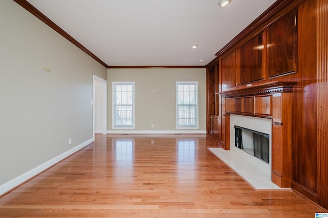 unfurnished living room featuring baseboards, a high end fireplace, crown molding, light wood-style floors, and recessed lighting