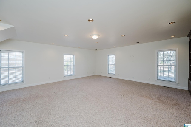 spare room featuring light carpet, a wealth of natural light, and baseboards