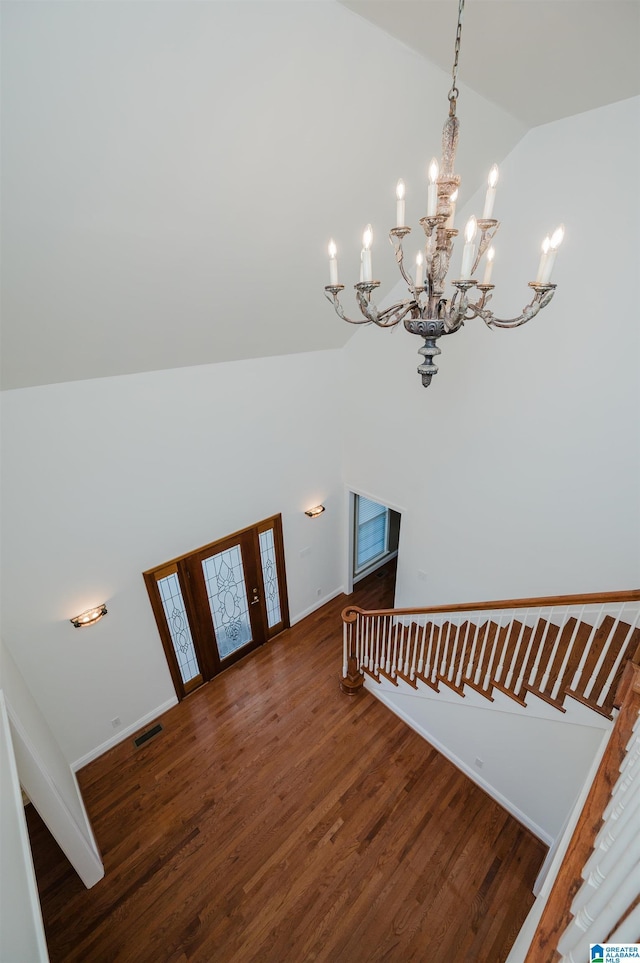 stairway with high vaulted ceiling, wood finished floors, visible vents, and baseboards