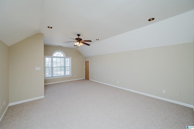 empty room featuring ceiling fan, light carpet, visible vents, baseboards, and vaulted ceiling