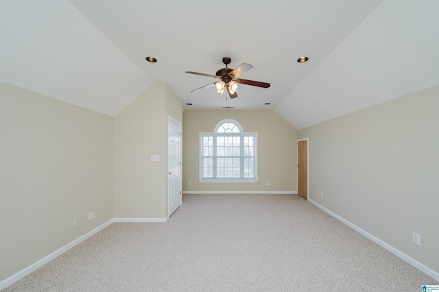 spare room featuring vaulted ceiling, ceiling fan, light colored carpet, and baseboards