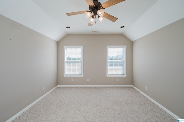 empty room featuring light colored carpet, lofted ceiling, visible vents, and baseboards