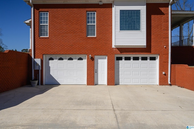 view of front of property with driveway, an attached garage, fence, and brick siding