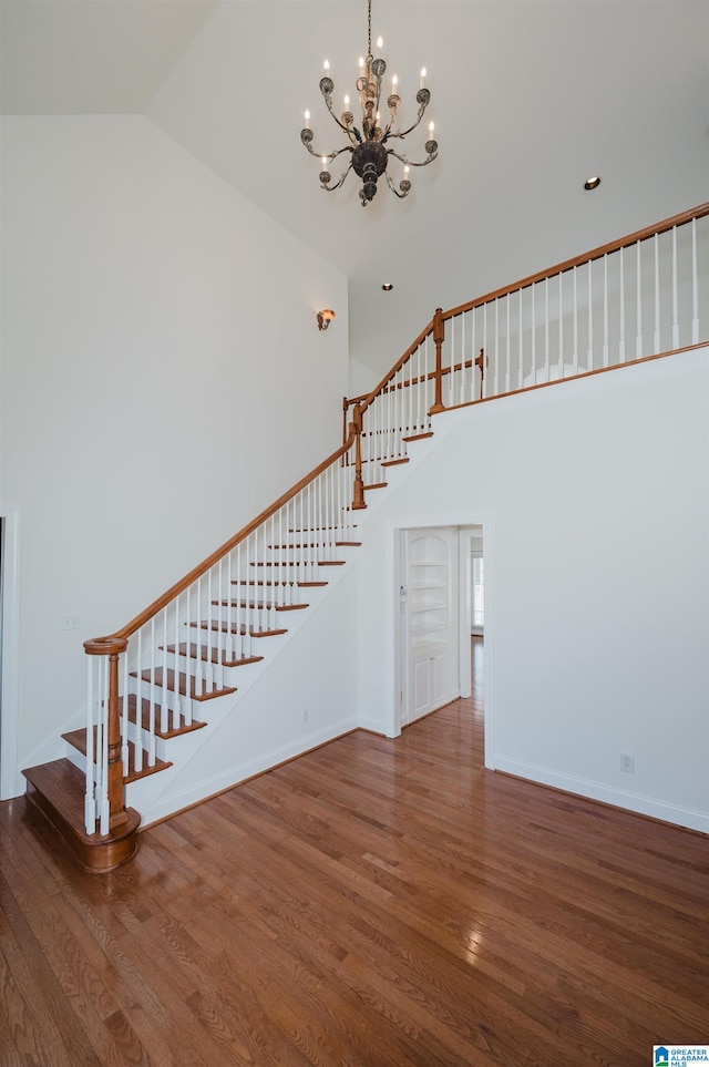 interior space featuring an inviting chandelier, baseboards, high vaulted ceiling, and wood finished floors