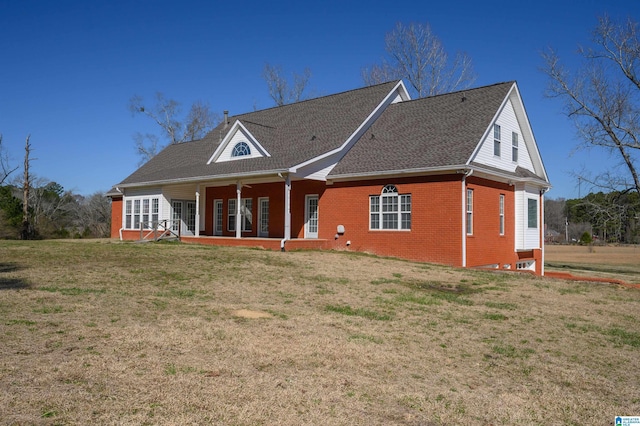 back of house featuring brick siding and a lawn