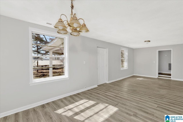 unfurnished dining area with plenty of natural light, visible vents, baseboards, and wood finished floors