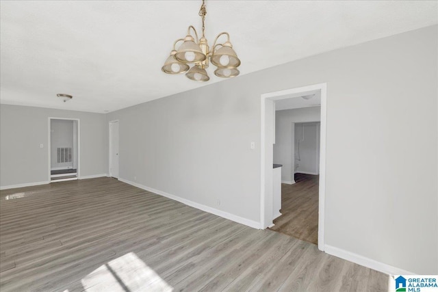 spare room with light wood-style flooring, visible vents, baseboards, and a notable chandelier