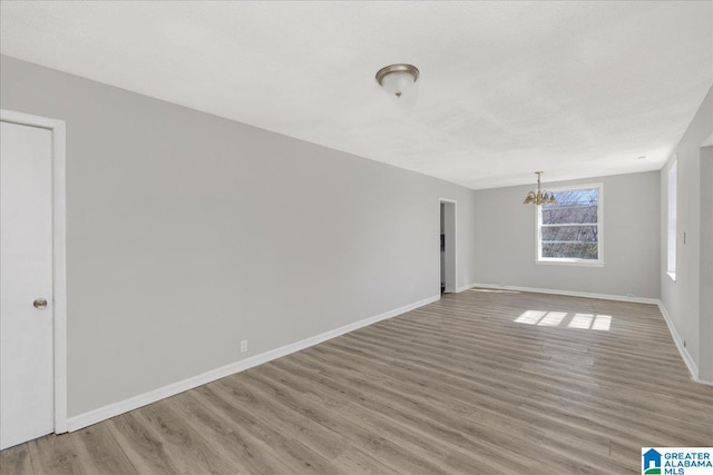 empty room with light wood-style flooring, baseboards, and a textured ceiling