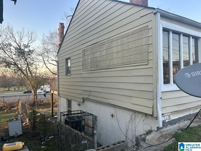 view of side of property with fence and a chimney