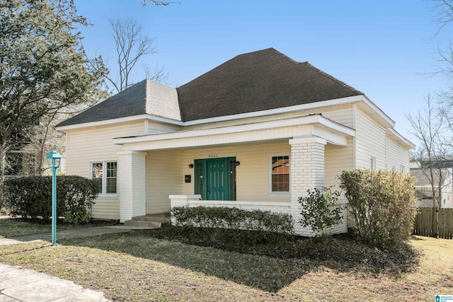 view of front of home with brick siding, fence, and roof with shingles