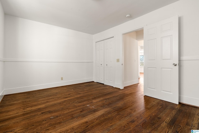 unfurnished bedroom with baseboards, dark wood finished floors, and a closet