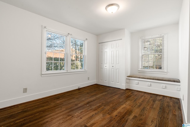 unfurnished bedroom featuring dark wood-style floors, a closet, and baseboards