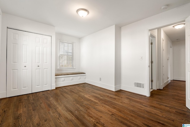 unfurnished bedroom with a closet, visible vents, dark wood finished floors, and baseboards