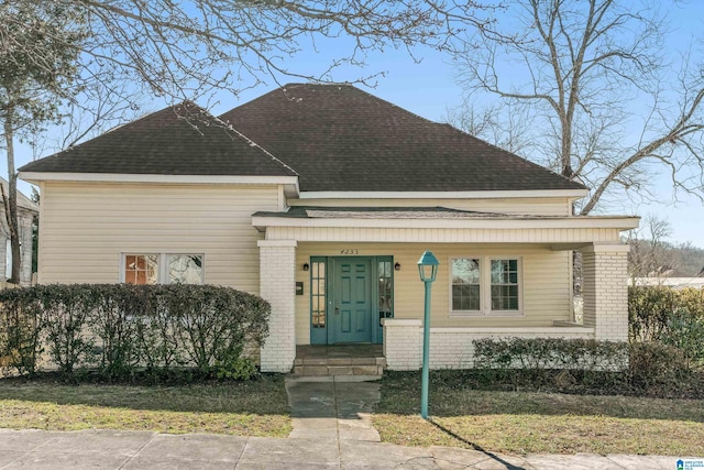 view of front of property with brick siding, a porch, and a shingled roof