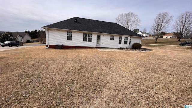 rear view of house featuring a yard, roof with shingles, and cooling unit