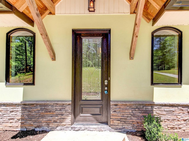 entrance to property with stone siding, board and batten siding, and stucco siding