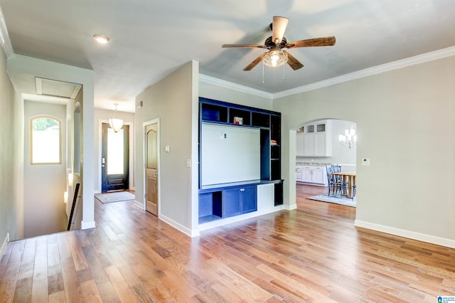 interior space featuring arched walkways, ornamental molding, light wood-style flooring, and baseboards