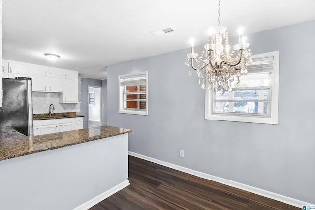 kitchen featuring visible vents, white cabinetry, baseboards, freestanding refrigerator, and tasteful backsplash