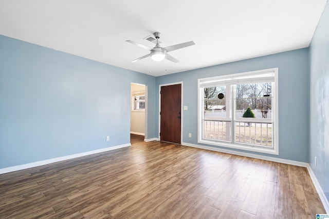 spare room with dark wood-type flooring, visible vents, ceiling fan, and baseboards