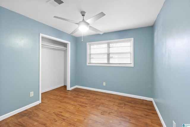 unfurnished bedroom featuring a closet, wood finished floors, visible vents, and baseboards