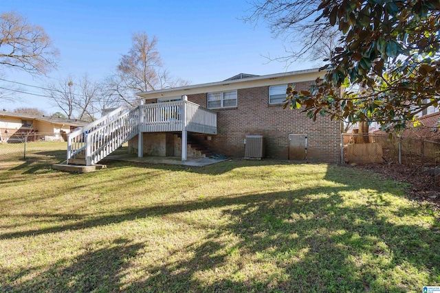 back of house with brick siding, a lawn, a fenced backyard, and stairs