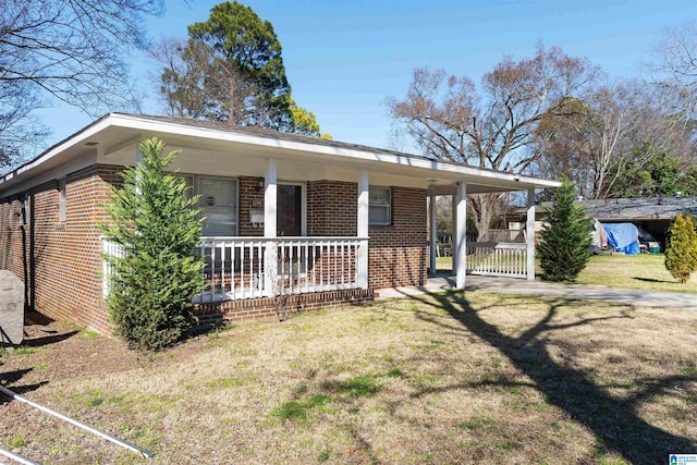 view of front facade with brick siding, a porch, and a front yard