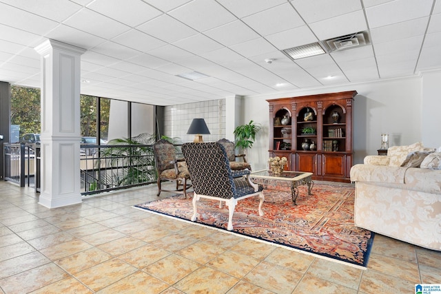 living area with visible vents, a drop ceiling, tile patterned floors, ornate columns, and floor to ceiling windows