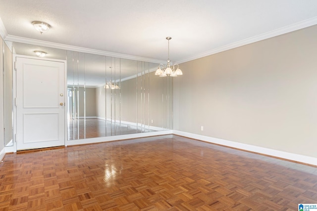 spare room featuring crown molding, baseboards, and an inviting chandelier