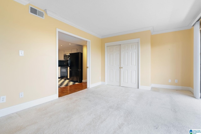 unfurnished bedroom with ornamental molding, freestanding refrigerator, visible vents, and carpet flooring