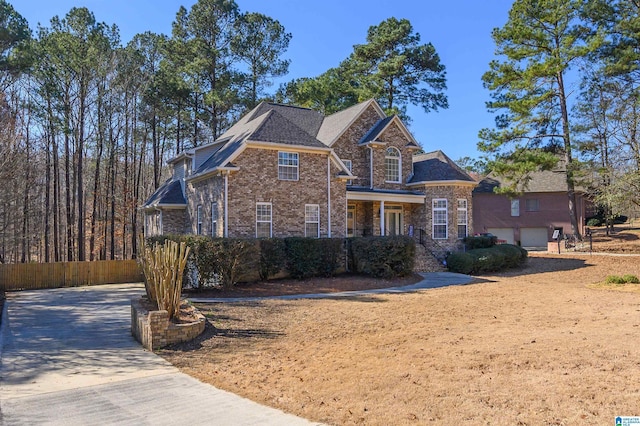 traditional-style house with a garage, driveway, fence, and brick siding