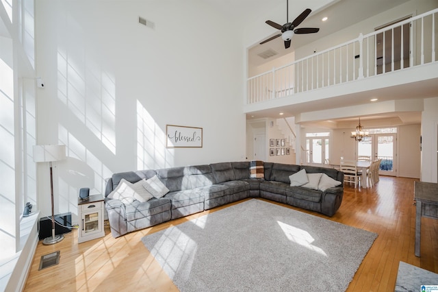 living room featuring stairway, wood-type flooring, a towering ceiling, and visible vents