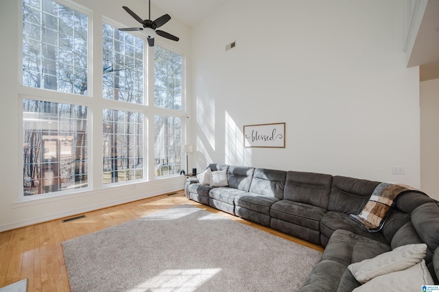 living room with plenty of natural light, a high ceiling, visible vents, and wood finished floors