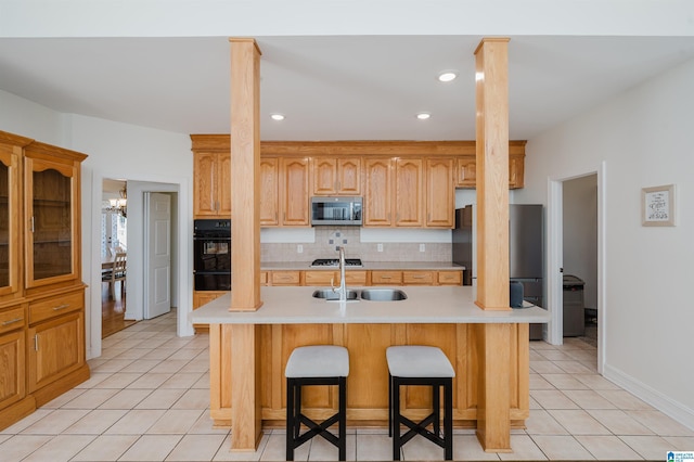 kitchen with decorative backsplash, appliances with stainless steel finishes, light countertops, a sink, and light tile patterned flooring