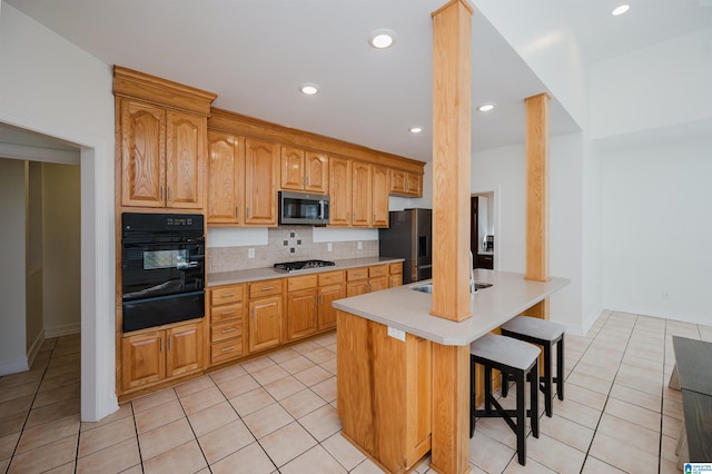 kitchen featuring light tile patterned floors, light countertops, backsplash, appliances with stainless steel finishes, and a kitchen bar