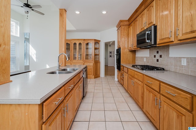 kitchen with light tile patterned flooring, stainless steel appliances, a sink, light countertops, and tasteful backsplash